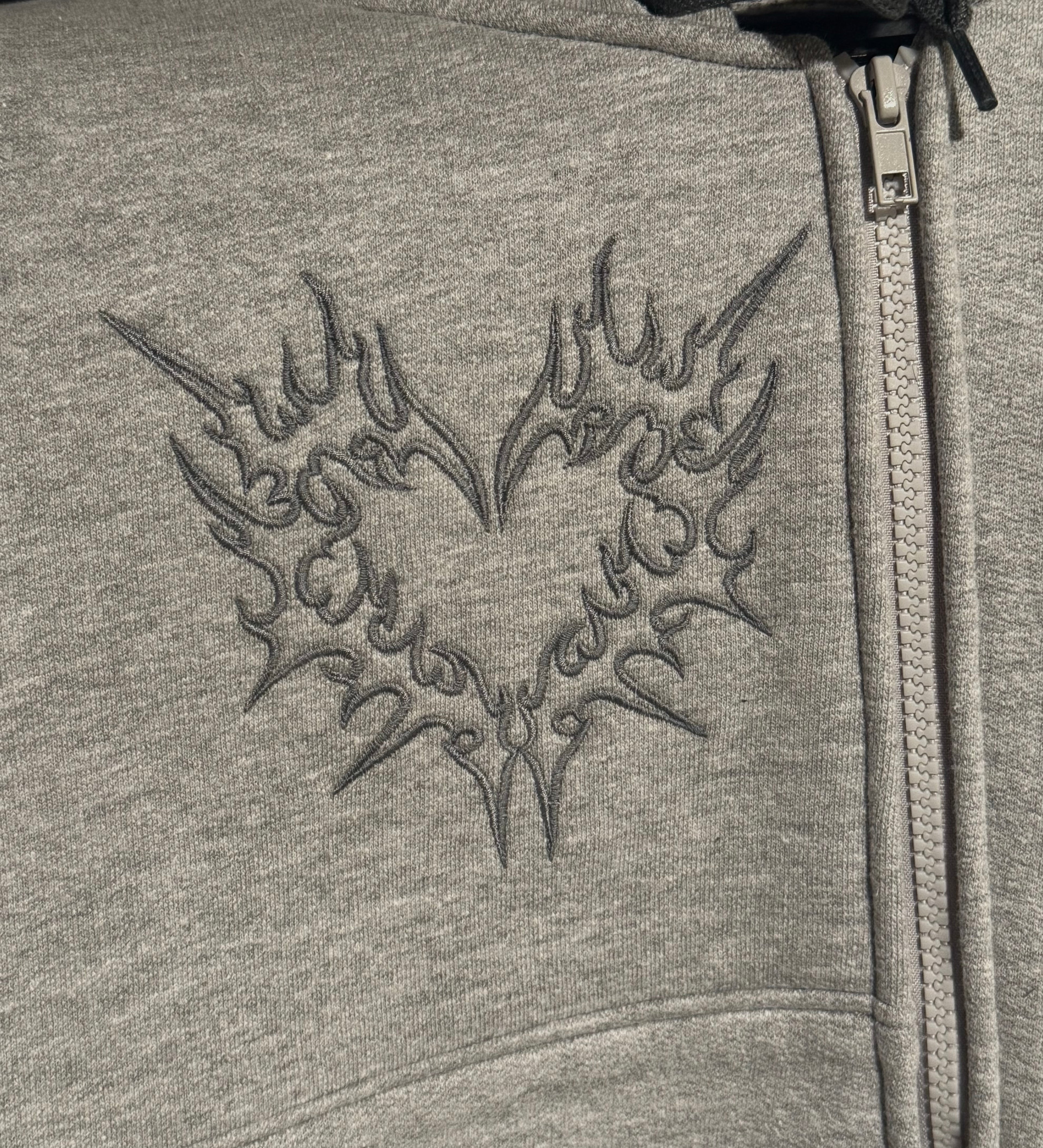 Gray hoodie with a detailed design on the chest and zipper.