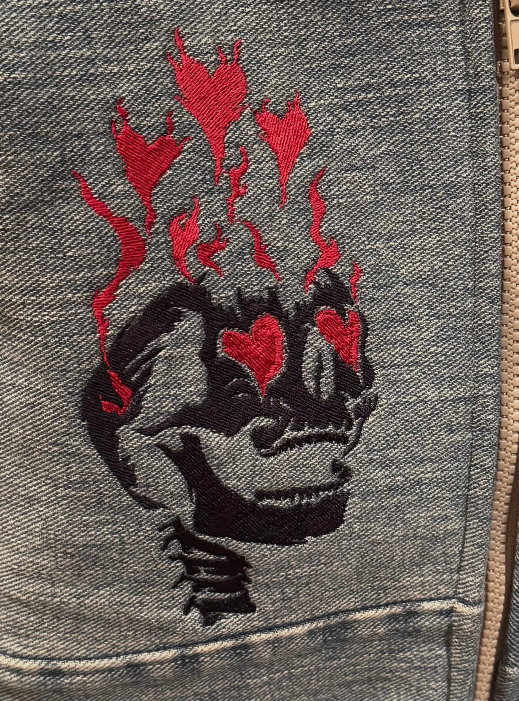 Embroidered design on a gray fabric with red hearts and black skull