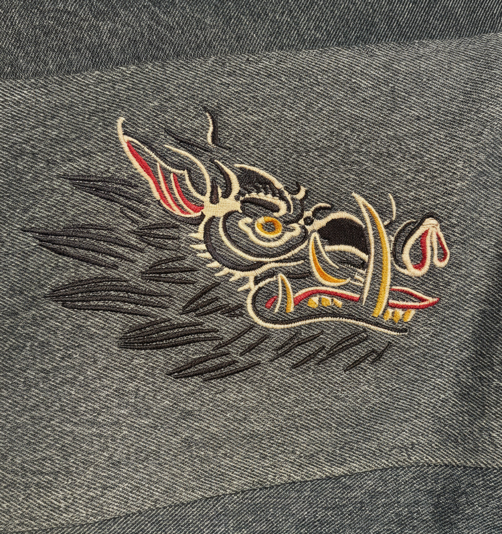 Embroidered dragon design on a gray fabric background