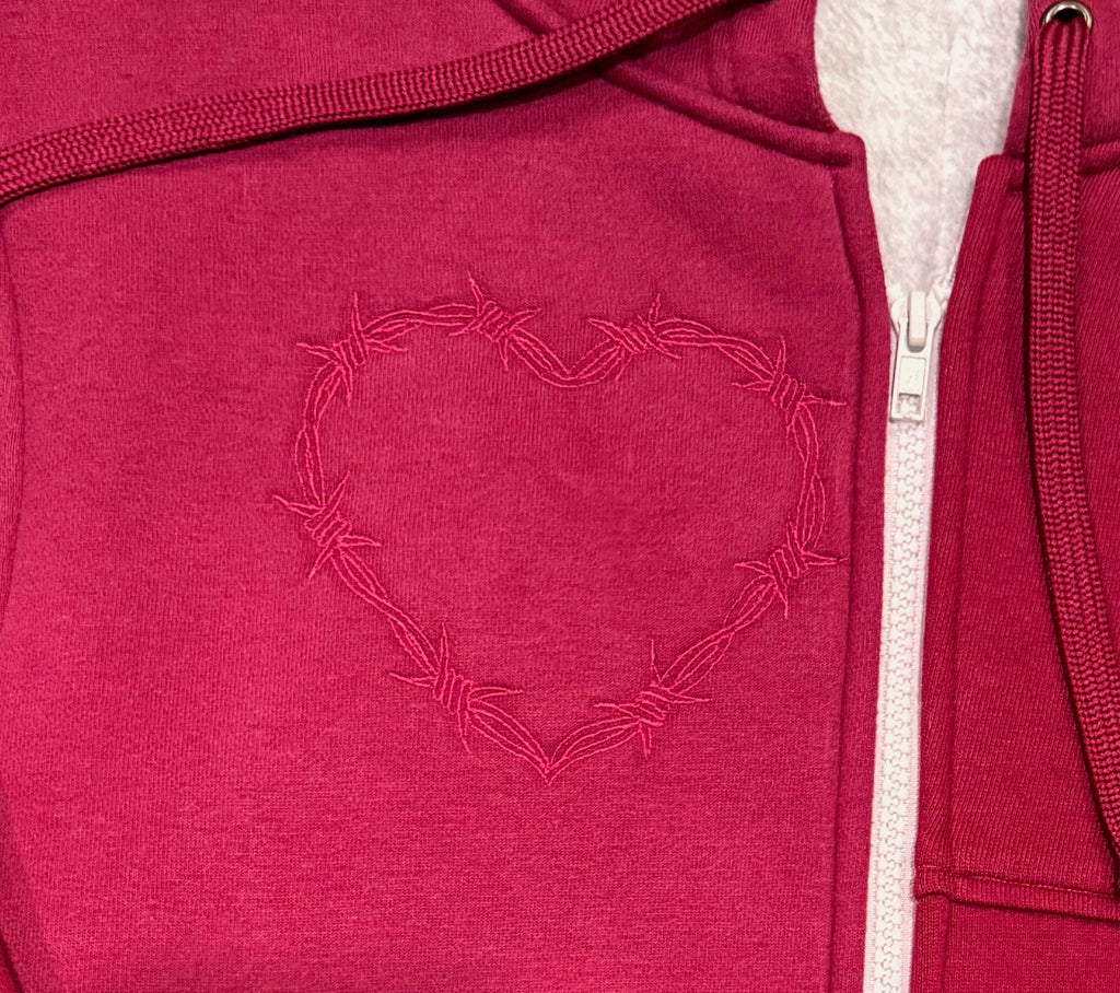 Red hoodie with a heart design made of barbed wire on the chest.